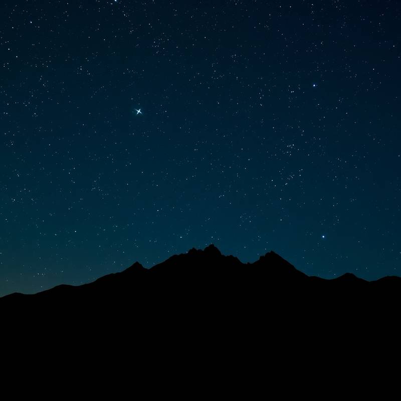 Starry night sky over a mountain range, relevant for night photography.